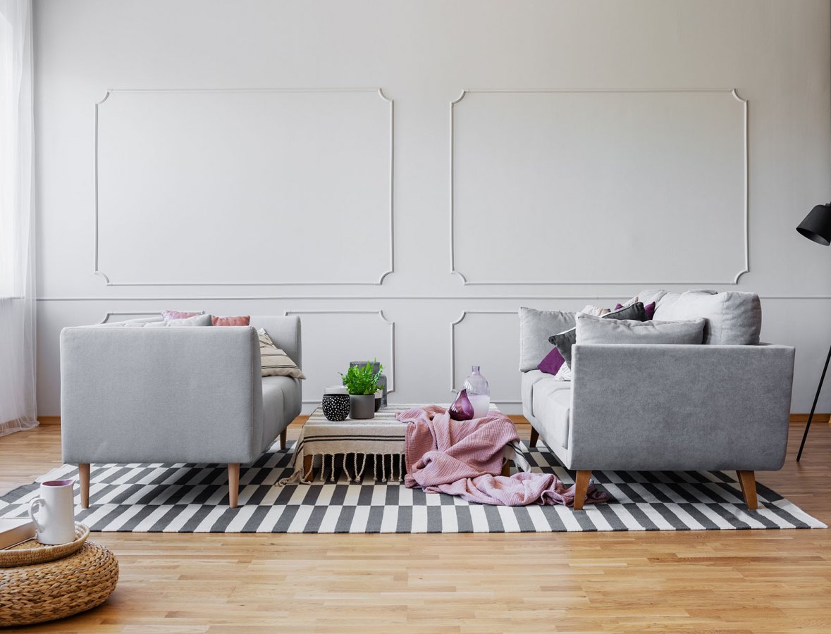 Salon ze sztukaterią na ścianie w odcieniach szarości. 